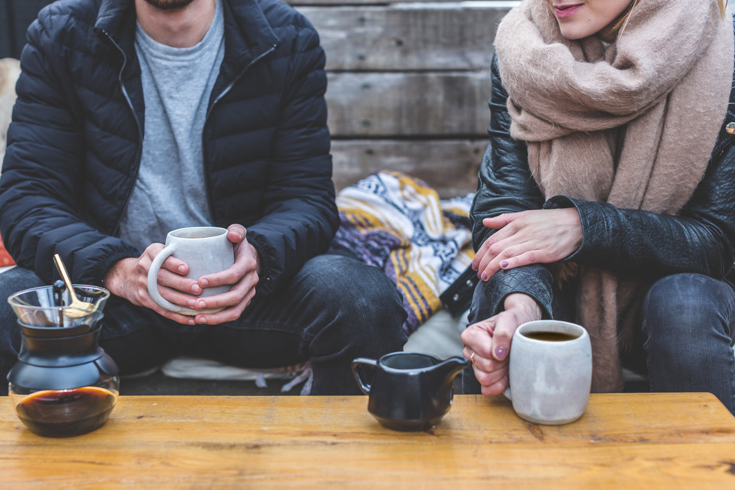 two people sitting at table with mugs of coffee