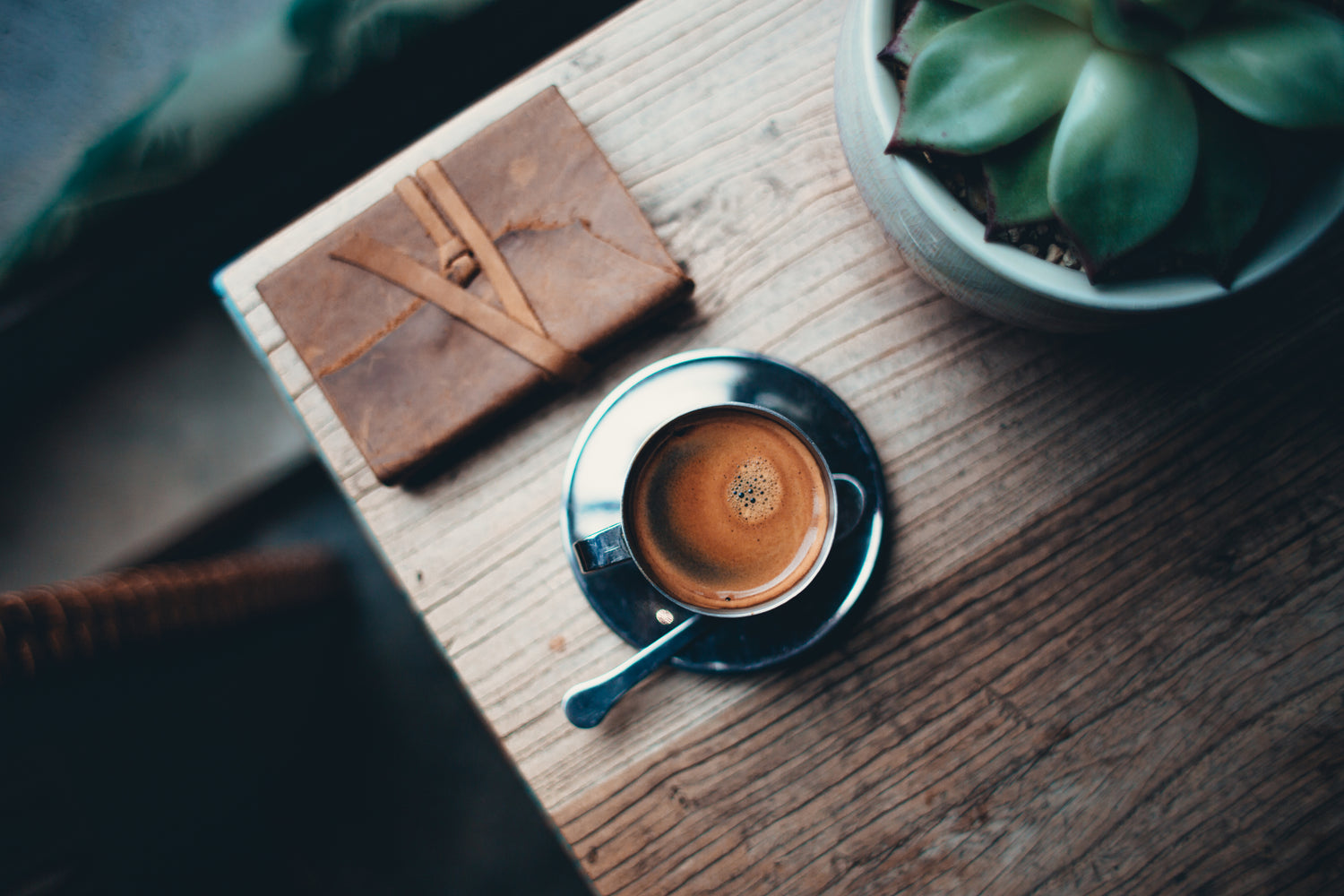 mug of coffee on wood table with succulent and journal