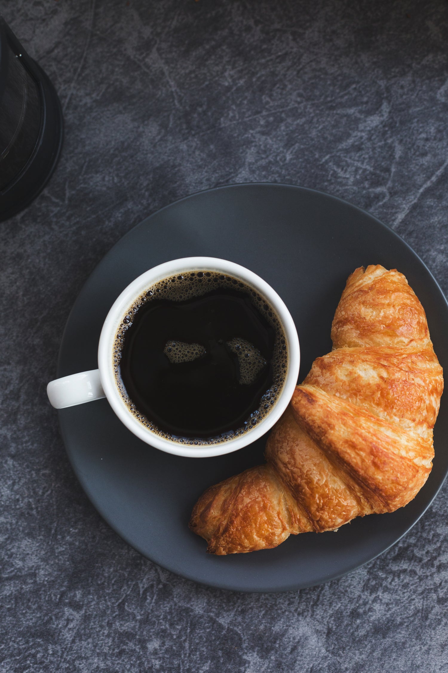 cup of coffee and crossiant on plate