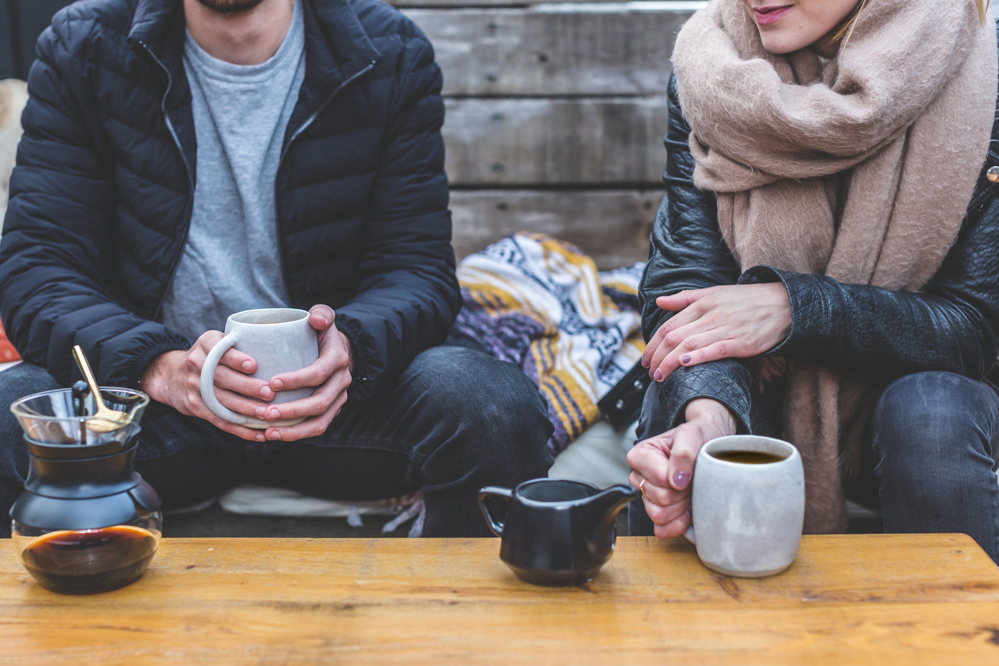 two people sitting at table with mugs of coffee